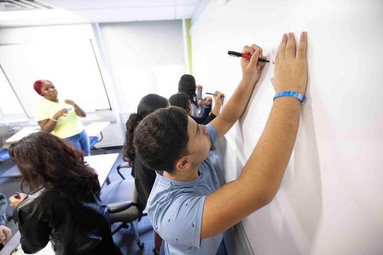 Student writing on white board with marker